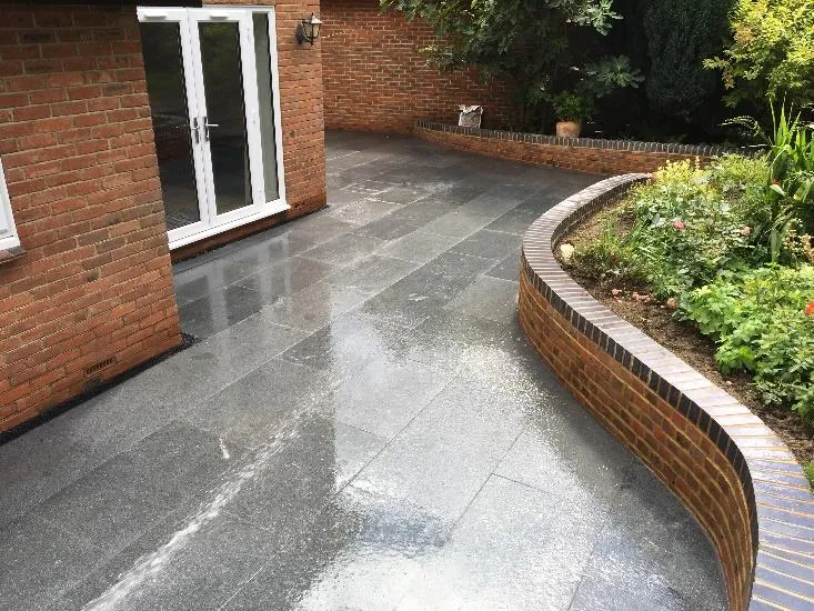 Curved brick planter wrapping a granite patio in Deal